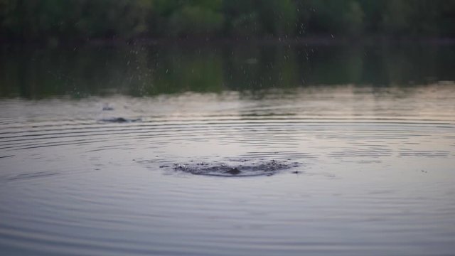 Stone skipping on water surface. Beautiful view of throwing a small flattened rock after being tossed across body of water bouncing off water many times and finally sinking in the lake.