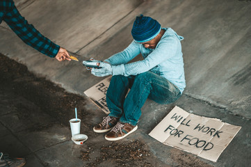 Beggars sitting under the overpass with a credit card and credit card swipe machine