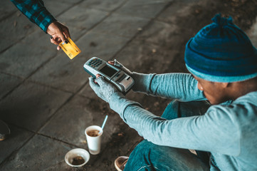 Beggars sitting under the overpass with a credit card and credit card swipe machine