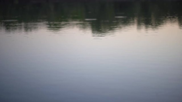 Stone skipping on water surface. Beautiful view of throwing a small flattened rock after being tossed across body of water bouncing off water many times and finally sinking in the lake.