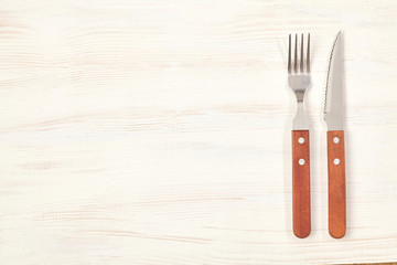 Fork and knife on wooden table with copy space. Top view.