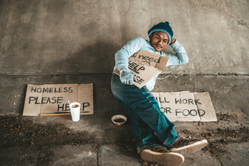 Begging under the bridge with a cup containing coins and instant noodles