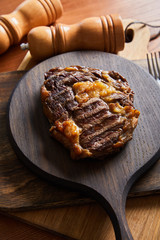 selective focus of tasty grilled steak served on wooden board near salt and pepper mills