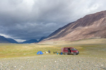 Tourists camping in Mongolian hills. Three tents under the open cloudy sky.