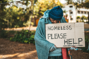 Beggars stand on the street with homeless messages please help.