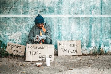 The beggars sat beside the street with a homeless message. Please help and work with food.