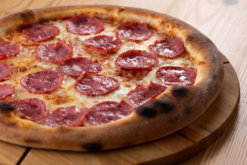 hearty italian pizza on a wooden board. cheese pizza with salami sausage