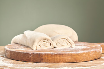 Fototapeta na wymiar Raw wheat dough on wooden cutting board. Close up