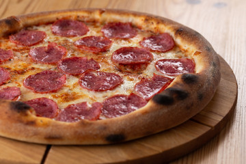 hearty italian pizza on a wooden board. cheese pizza with salami sausage