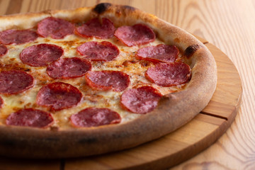 hearty italian pizza on a wooden board. cheese pizza with salami sausage