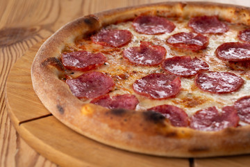 hearty italian pizza on a wooden board. cheese pizza with salami sausage