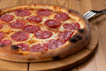 hearty italian pizza on a wooden board. cheese pizza with salami sausage