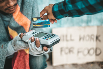 Beggars sitting under the overpass with a credit card and credit card swipe machine