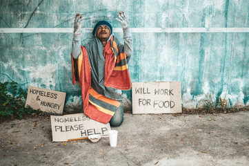 The beggars sat beside the street with a homeless message. Please help and work with food.