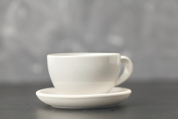 Obraz na płótnie Canvas A white cup on the black table. On gray background
