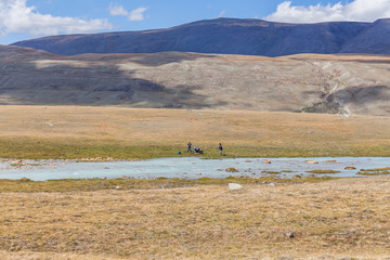 Fototapeta premium Typical view of Mongolian landscape. Mongolian steppe, Altai, Mongolia. Tourists relax near the lake.