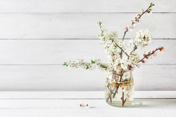 Fresh Small white flowers bouquet on white table in front of wooden wall. View with copy space