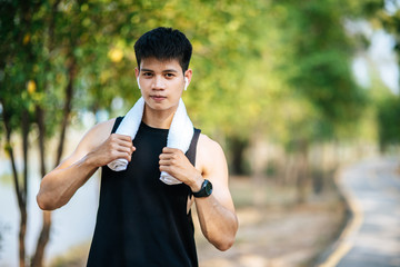 A man in a black shirt stood and held a handkerchief over his neck to wipe his face.