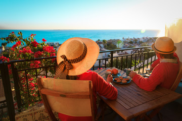 romantic couple having breakfast on balcony terrace with sea view