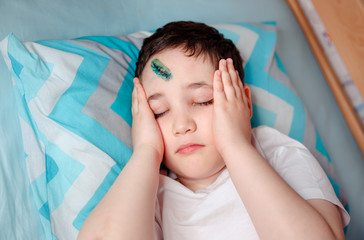 The child is holding his head because of a severe headache associated