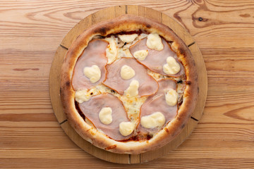 hearty italian pizza on a wooden board. crispy pizza with ham, mushrooms and cheese