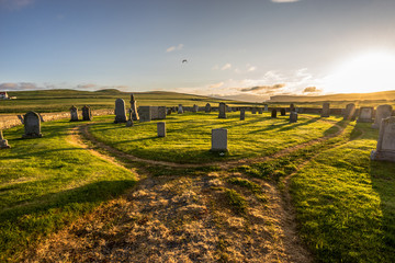 old hillswick cemetery full of tombstones on the Shetland (Scotland, UK) on a panoramic sunset with dramatic warm light and illuminated green grass