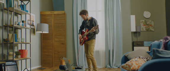 DX Caucasian male playing his electric guitar at home, practicing during quarantine