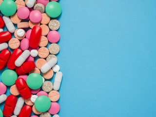 Colorful, green, red, white pills on blue background, flat lay
