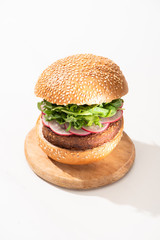 delicious vegan burger with radish and arugula on wooden board on white background