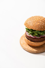 delicious vegan burger with radish and arugula on wooden board on white background