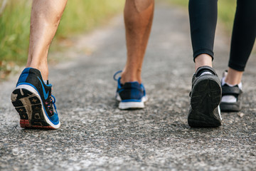 Fototapeta na wymiar Runner woman and man feet running on road closeup on shoe. Sports healthy lifestyle concept.