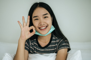 Girl wearing sanitation mask, striped shirt, and hand symbol, okay