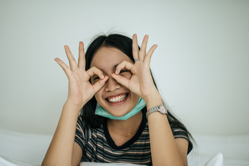 Girl wearing sanitation mask, striped shirt, and hand symbol, okay