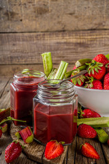 Homemade strawberry rhubarb jam or sauce, with fresh rhubarb and strawberries and spices, wooden rustic background copy space