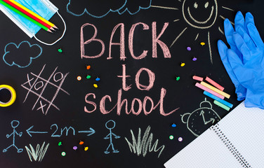 Fototapeta na wymiar Back to school background written by crayons on the blackboard also with face mask and latex gloves to protect from coronavirus.