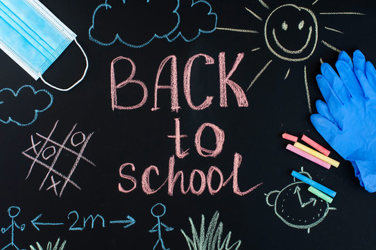 Back to school background written by crayons on the blackboard also with face mask and latex gloves to protect from coronavirus.