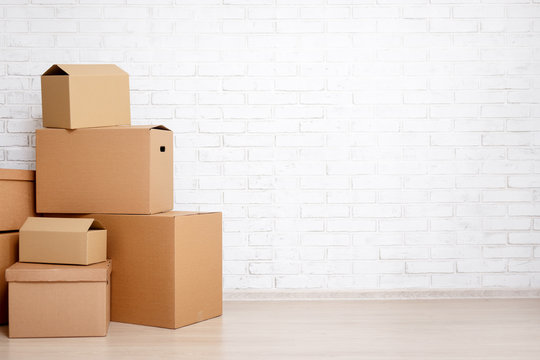 moving day concept - cardboard boxes and copy space over white brick wall