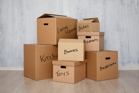 moving day - brown cardboard boxes with belongings stacked over gray background