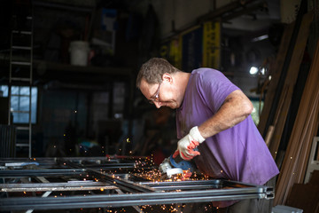 A man is cutting metal in a garage.