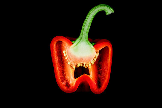 peperone rosso tagliato a met&agrave; su sfondo nero 
