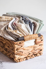 Obraz premium kitchen textile. stack of fabrics in different colors and textures, close-up. Kitchen towels on white background. Many fabric kitchen napkins in a wicker basket. Props for foodphotography