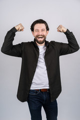 Young man with beard showing a gesture of power, he cheerfully laughs