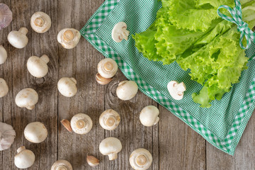 Mushrooms on a wooden table and fresh lettuce leaves on a green napkin.