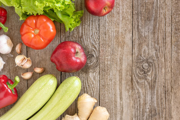 Set of zucchini, apples, tomatoes, red pepper, lettuce and garlic on a wooden background. Space for text, top view.
