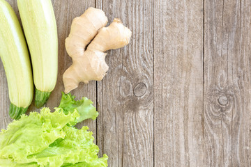 Zucchini, fresh lettuce and ginger on a wooden background. Template for the text.
