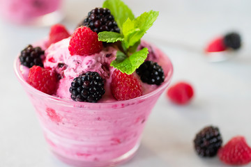 Homemade berry sorbet in glass cups, mint leaves and fresh berries on gray background.