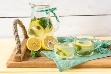 Lemonade with lemon and mint on a rustic wooden tray.