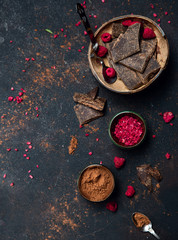 Bars of black chocolate and a sublimated raspberry as a decoration in the coconut plate. Raw vegan chocolate. Lactose free chocolate. Gluten free chocolate. Without artificial dyes.