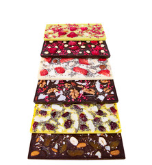 Bars of multicolor  chocolate with sublimated berries, coconut nuts and seeds on the white background. Raw vegan chocolate. Lactose free chocolate. Gluten free chocolate. Without artificial dyes.