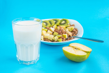 muesli with kiwi and apple with milk on a blue background. healthy food. many nutrients.